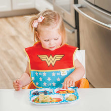 Girl wearing Wonder Woman Caped SuperBib eating off of Wonder Woman melamine plate