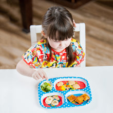 girl sitting at table in Wonder Woman Junior Bib with melamine plate